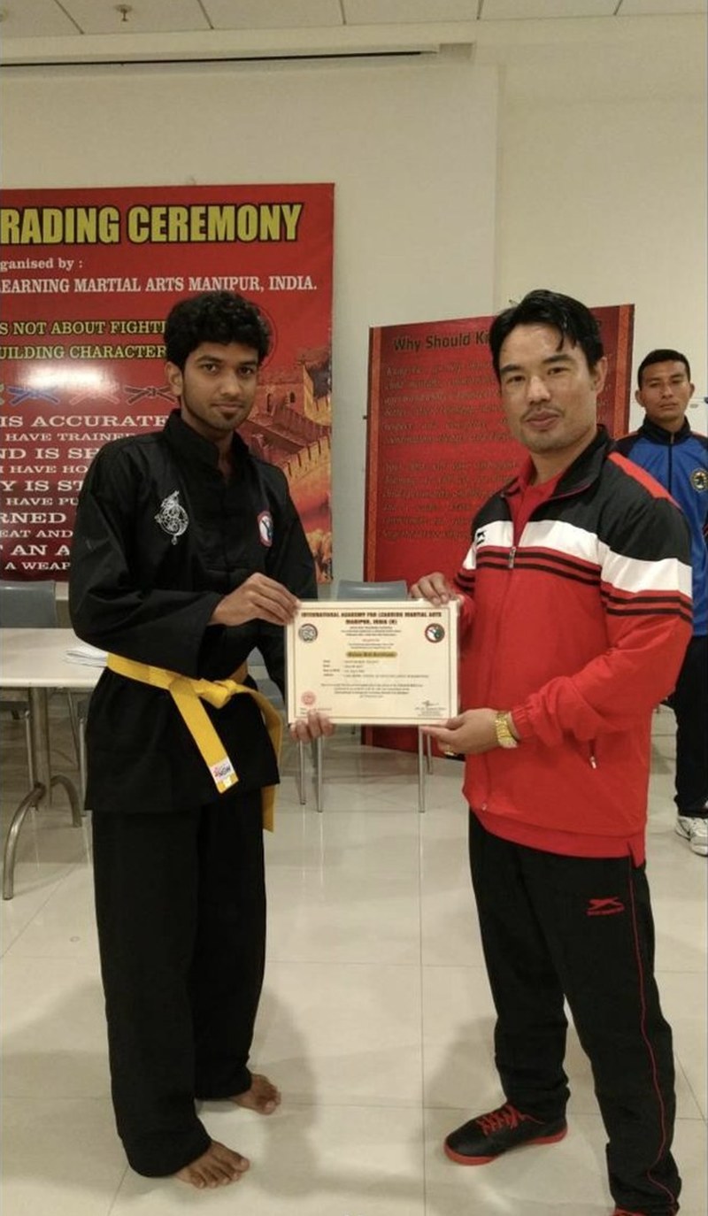 Savan receiving his yellow-belt grading certificate from his kung fu master