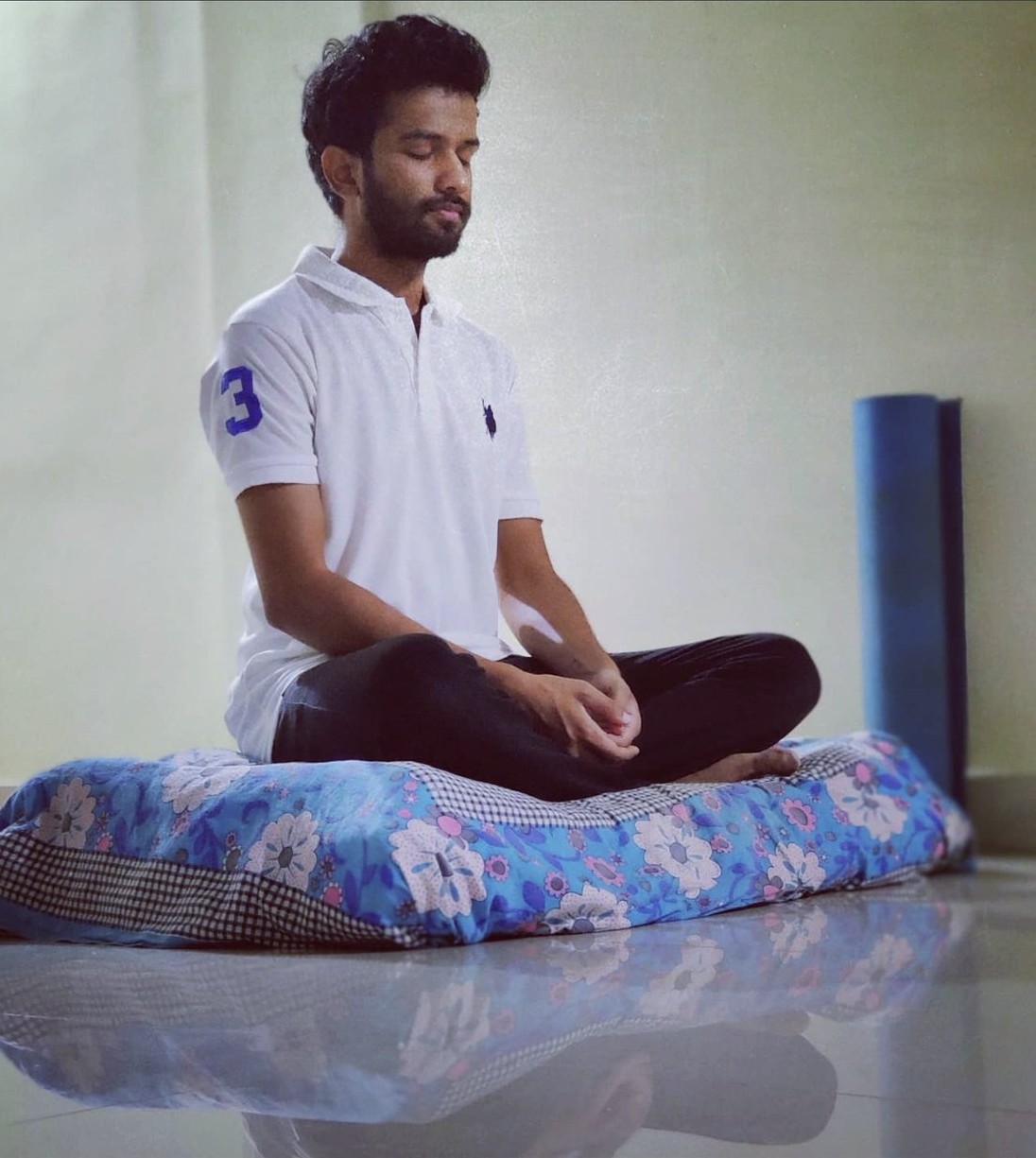 Savan sitting in meditation on a floral cushion